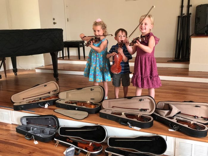 Children holding their violins - music helps with social and emotional intelligence